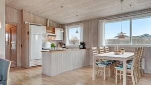 Et moderne køkken med træskabe, indbygget ovn og et spiseområde med bord og stole.