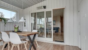 Et spiseområde med et træbord, hvide stole og hængende lamper.