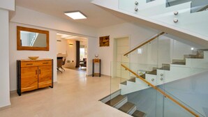 Ein modernes Interieur mit einem Holzkabinett, einer Glastreppe und einem Essbereich.
