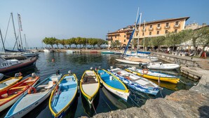 A marina with various boats docked, a building with balconies, and trees along the waterfront.
