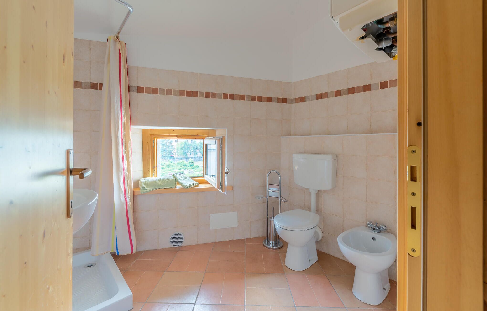 Un baño con ventana, inodoro, bidé y bañera.