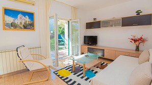 Ein Wohnzimmer mit Glastisch, einer Couch, einem Fernseher und einem Gemälde eines Gebäudes.