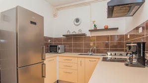 Eine kleine Küche mit Edelstahlkühlschrank, Mikrowelle, Spüle und Kaffeemaschine.