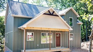 A two-story house with a front porch, a brown door, and a small attached garage.