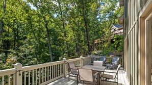 A wooden deck with a table and chairs, surrounded by trees.