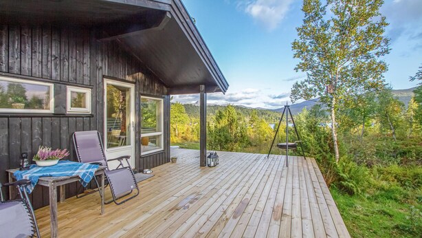 A wooden deck with a table and chairs, a swing, and a view of a lake and mountains. - 4 bedroom awesome home in Sykkylven (Sykkylven)