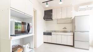 A modern kitchen with stainless steel appliances, white cabinetry, and a dishwasher. - Regina Ishigaki Blue Stage (Ishigaki)