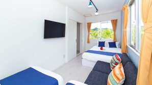 A modern hotel room with two beds, a flat-screen TV, and a sofa. - Regina Ishigaki Blue Stage (Ishigaki)