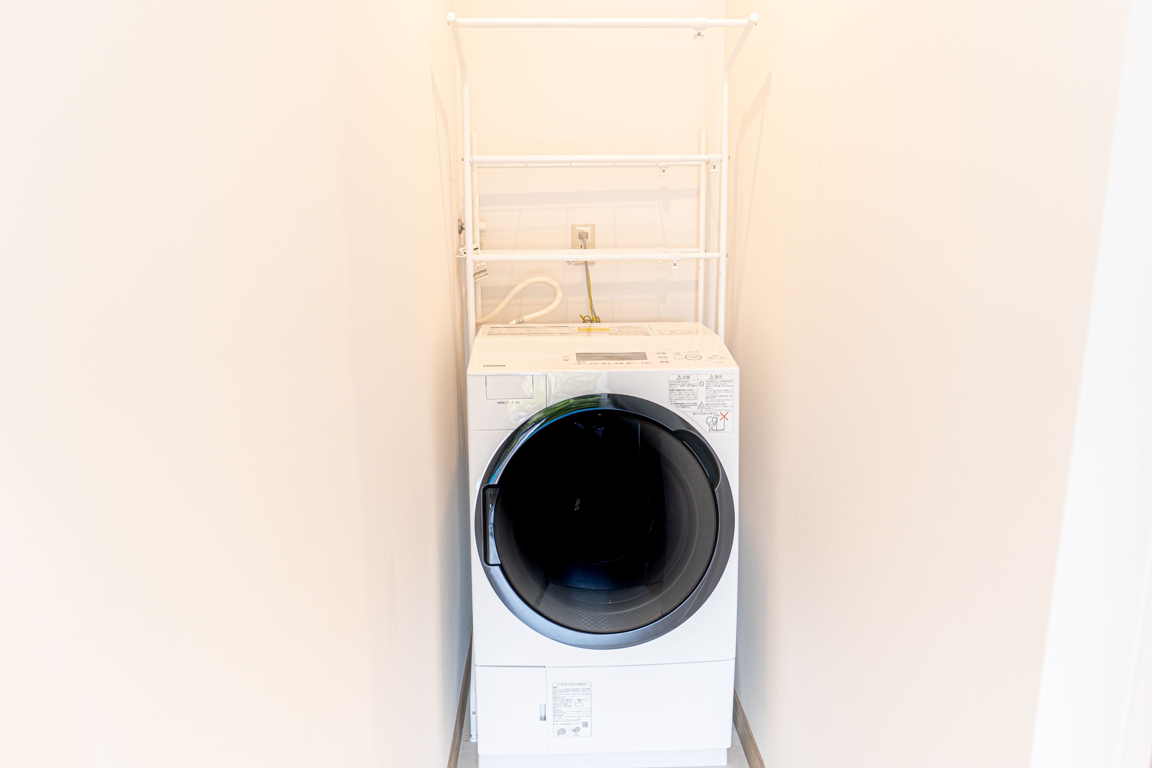 Een voorlader wasmachine met bedieningspaneel en een droogrek erboven.