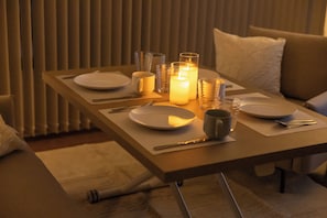 Enjoy a warm meal in the comfort of your room, with a dining table set for two and a soft candlelight ambiance.