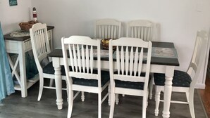 En matplats med ett vitt bord och stolar, en tavla som hänger på väggen och en liten korg på bordet.