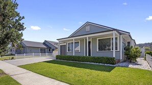 Une maison de plain-pied dotée d’un porche abrité, d’une pelouse bien entretenue et d’une allée gravillonnée.