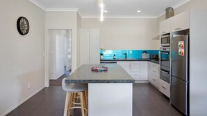Une cuisine moderne dotée d’un îlot central, d’appareils électroménagers en acier inoxydable et d’un revêtement mural lumineux.