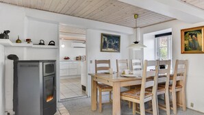 A modern kitchen with white cabinets, a built-in stove, and a dining area with a wooden table and chairs. - Gorgeous home in Højer with WiFi (Højer)