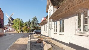 A traditional building with a thatched roof, large windows, and a visible flag. - Gorgeous home in Højer with WiFi (Højer)