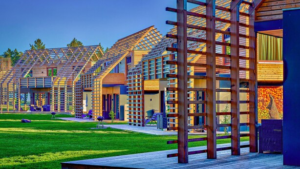 Un bâtiment moderne comprenant plusieurs logements, une terrasse en bois et un espace verdoyant.