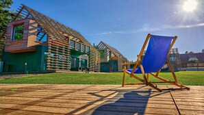Un bâtiment moderne doté d’un toit en pente, d’une terrasse en bois et d’une chaise de plage bleue.