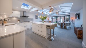 Una cocina moderna con una isla central, tragaluces y un comedor con una mesa redonda y sillas.
