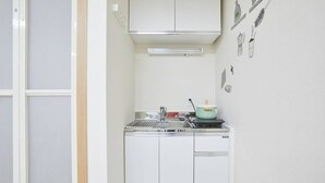 A compact kitchen with white cabinets, a stainless steel sink, and a microwave.