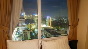 A hotel room with a large window offering a nighttime city view. - Fantastic View 2BR Apartment at FX Residence Sudirman (Jakarta)