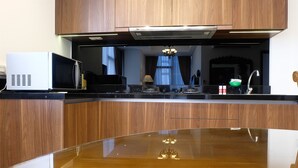 Une cuisine avec des meubles en bois, un four à micro-ondes et un plan de travail en acier inoxydable.