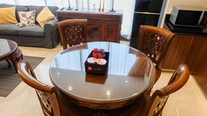 Un coin repas avec une table ronde en verre, des chaises en bois et une caisse de bouteilles de Coca-Cola.