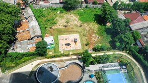 Vue aérienne d’un parc comprenant une aire de jeux, une fontaine circulaire et un court de tennis.