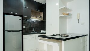 Une cuisine moderne dotée d’un réfrigérateur en acier inoxydable, d’un plan de travail en carreaux noirs, de meubles blancs et d’un îlot central avec un dessus noir.