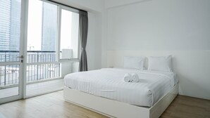 Une chambre d’hôtel moderne dotée d’une grande fenêtre, d’un lit avec du linge de lit blanc et offrant une vue sur le paysage urbain.