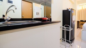 Eine moderne Küche mit einem Edelstahl-Spülbecken, einem Kühlschrank und einem Metallregal.