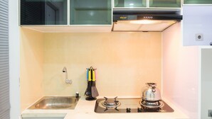 A compact kitchen with a gas stove, a sink, and a window above the counter.