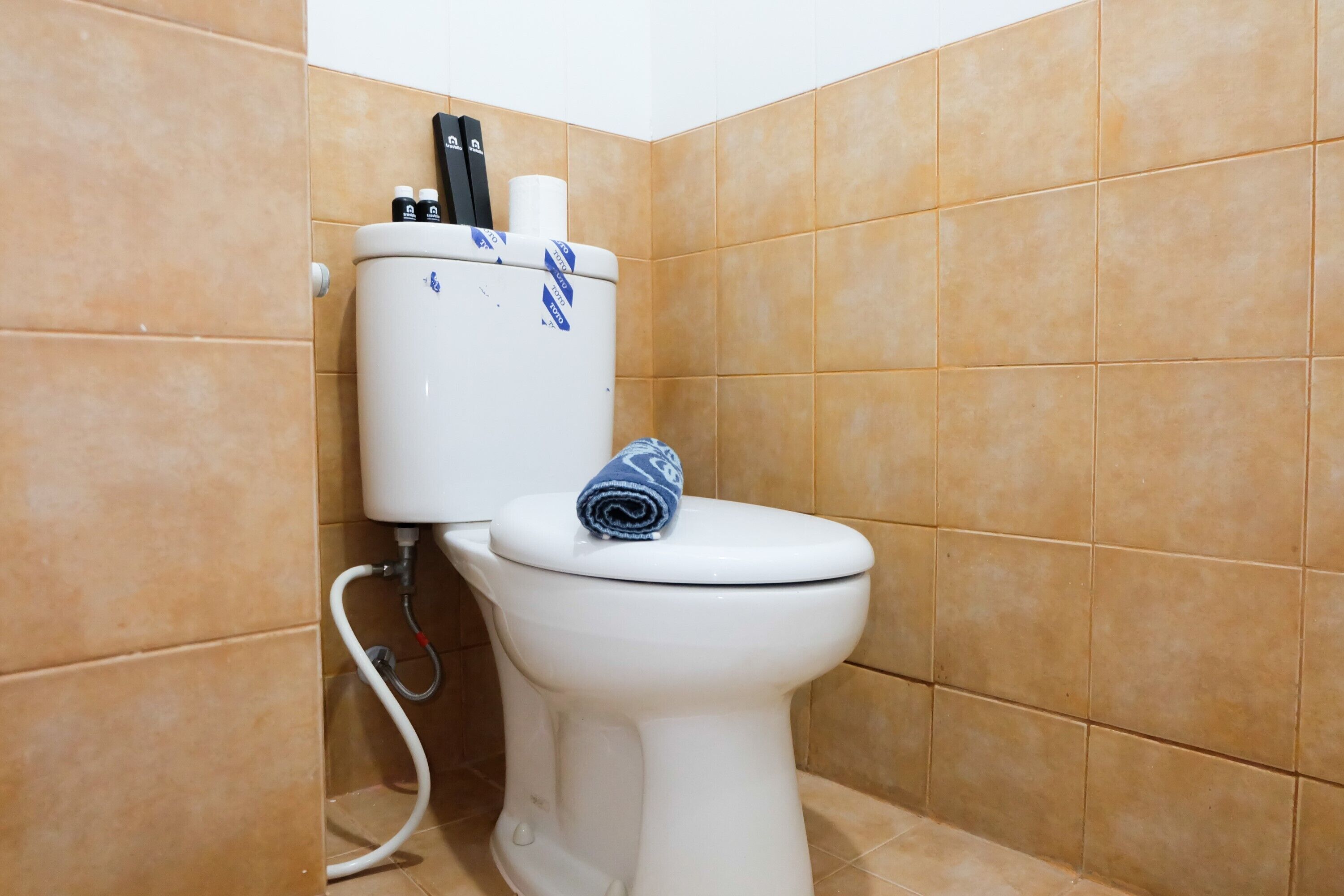 Valkoinen wc-istuin, jonka päällä on sininen pyyhe, wc-paperiteline ja bidee.
