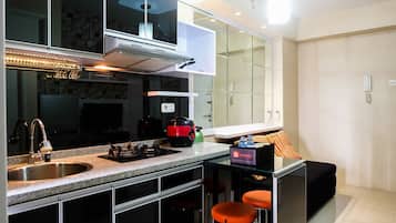 Una cucina moderna con lavello in acciaio inossidabile, piano cottura integrato e cappa aspirante. Sono presenti due sgabelli da bar e un piccolo tavolo con una scatola etichettata 'TraVello'.