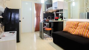 A compact kitchen with a refrigerator, stove, and bar stools.