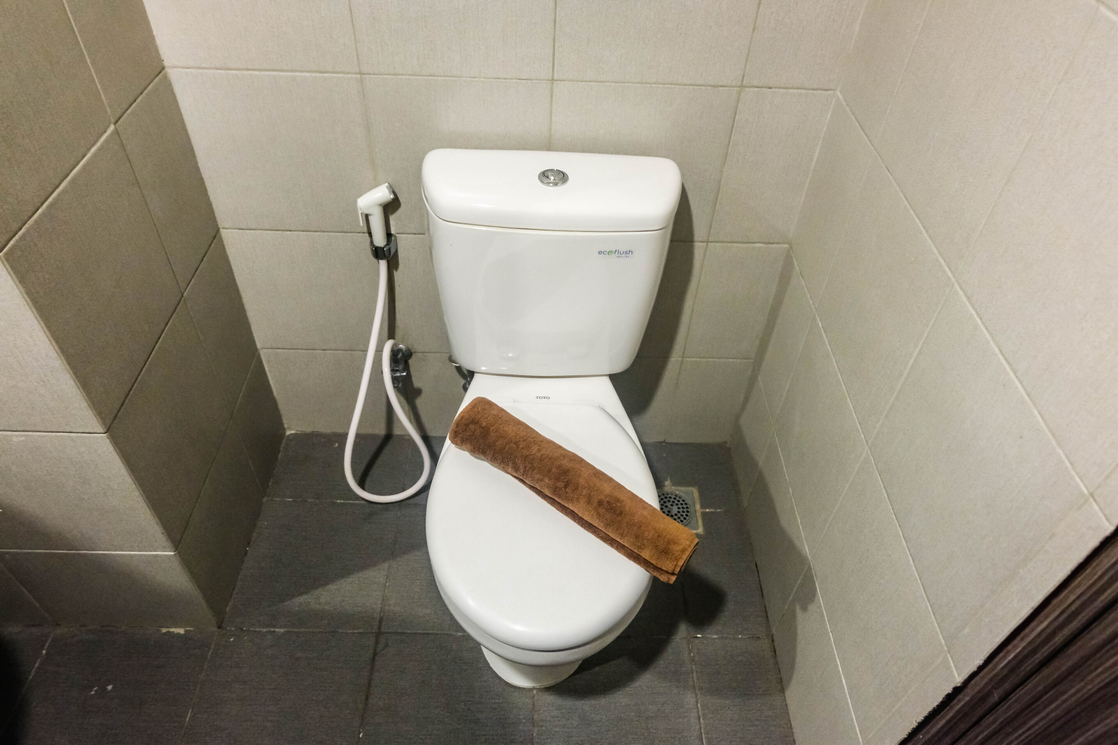A toilet with a towel on the seat and a bidet attachment.