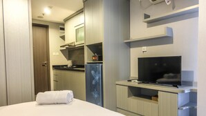 A hotel room with a bed, a TV, a kitchenette, and a bathroom. - Brand New Studio Room at Bintaro Icon Apartment (South Tangerang)