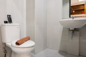 Un baño con inodoro, lavamanos y espejo.
