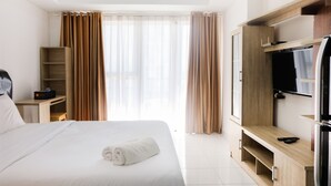 Une chambre d’hôtel avec un lit, une télévision, une armoire en bois et un bureau.
