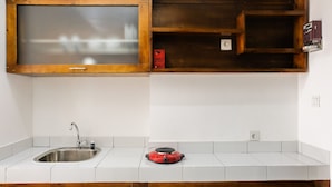 Une cuisine dotée d’un évier en acier inoxydable, d’un appareil électroménager rouge, de meubles de rangement en bois et d’une fenêtre située au-dessus de l’évier.