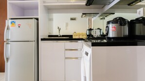 A compact kitchen with white cabinets, a built-in oven, a coffee maker, and a microwave. - Nice 1BR Apartment at M-Town Signature (Gading Serpong)
