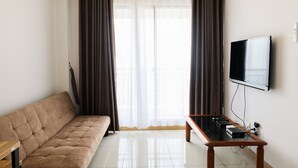 A modern living room with a sofa, a coffee table, and a flat-screen TV mounted on the wall. - Nice 1BR Apartment at M-Town Signature (Gading Serpong)