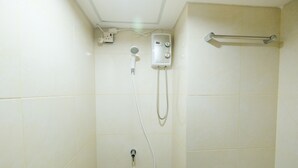Ducha con cabezal de ducha de mano, panel de control en la pared y barra para toallas.