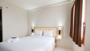 Habitación de hotel con una cama grande, ropa de cama blanca y un cabecero con luces fijadas a la pared.