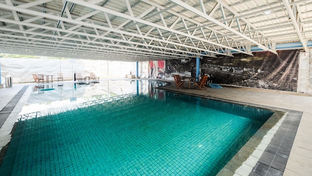 Una piscina interior con suelo de baldosas y estructura de techo metálica.