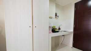 Una pequeña cocina con cubierta blanca, un lavamanos y una puerta de madera oscura.