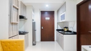 A modern kitchen with white cabinets, a microwave, a stove, and a sink. - Premium 1BR Apartement At Grand Sungkono Lagoon (Surabaya)