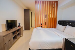 A hotel room with a bed, a TV on a wooden console, and a sliding door. - Elegant 1BR at Grand Kamala Lagoon Apartment (Bekasi)