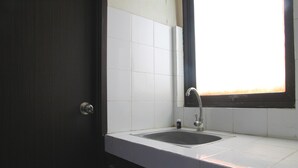 A bathroom with a white sink, a mirror, and a window with a view of the outside. - Best Deal Studio at Kebagusan City Apartment (Jakarta)