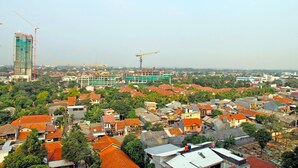 A densely populated urban area with various buildings, including residential houses and a construction site with cranes. - Best Deal Studio at Kebagusan City Apartment (Jakarta)