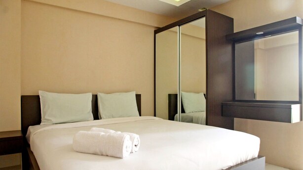 A hotel room with a large bed, a mirror, and a wardrobe. - Best Deal Studio at Kebagusan City Apartment (Jakarta)
